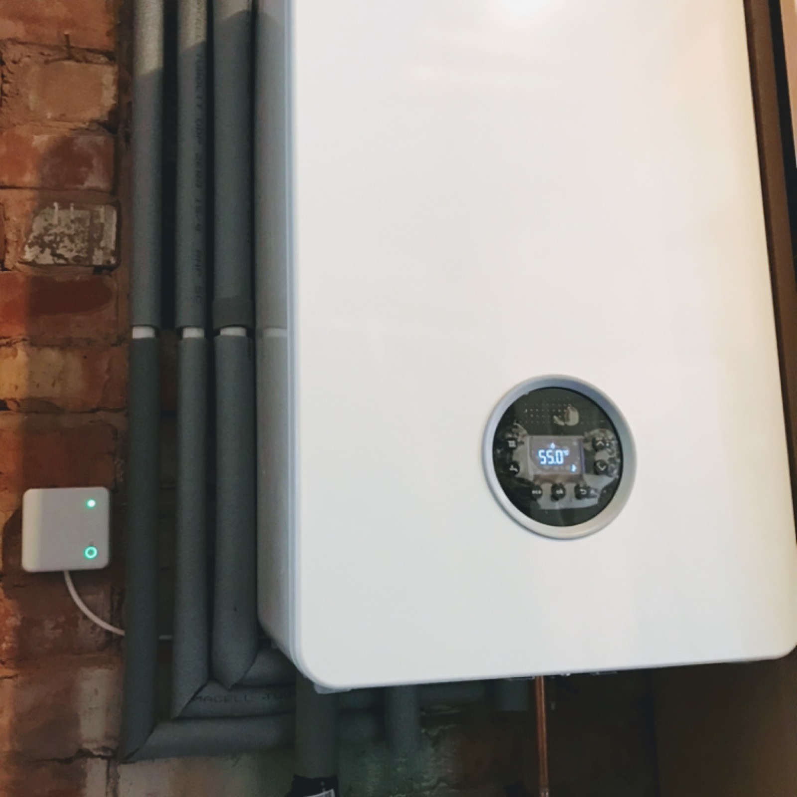 A modern Worcester boiler running at 55 degrees with a smart controller on the wall beside it