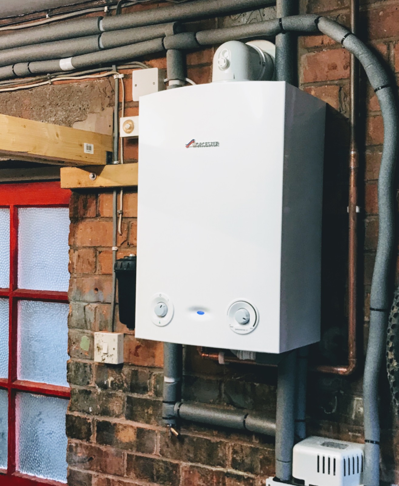 A Worcester combi boiler fitted in a garage with pipework dropped behind it