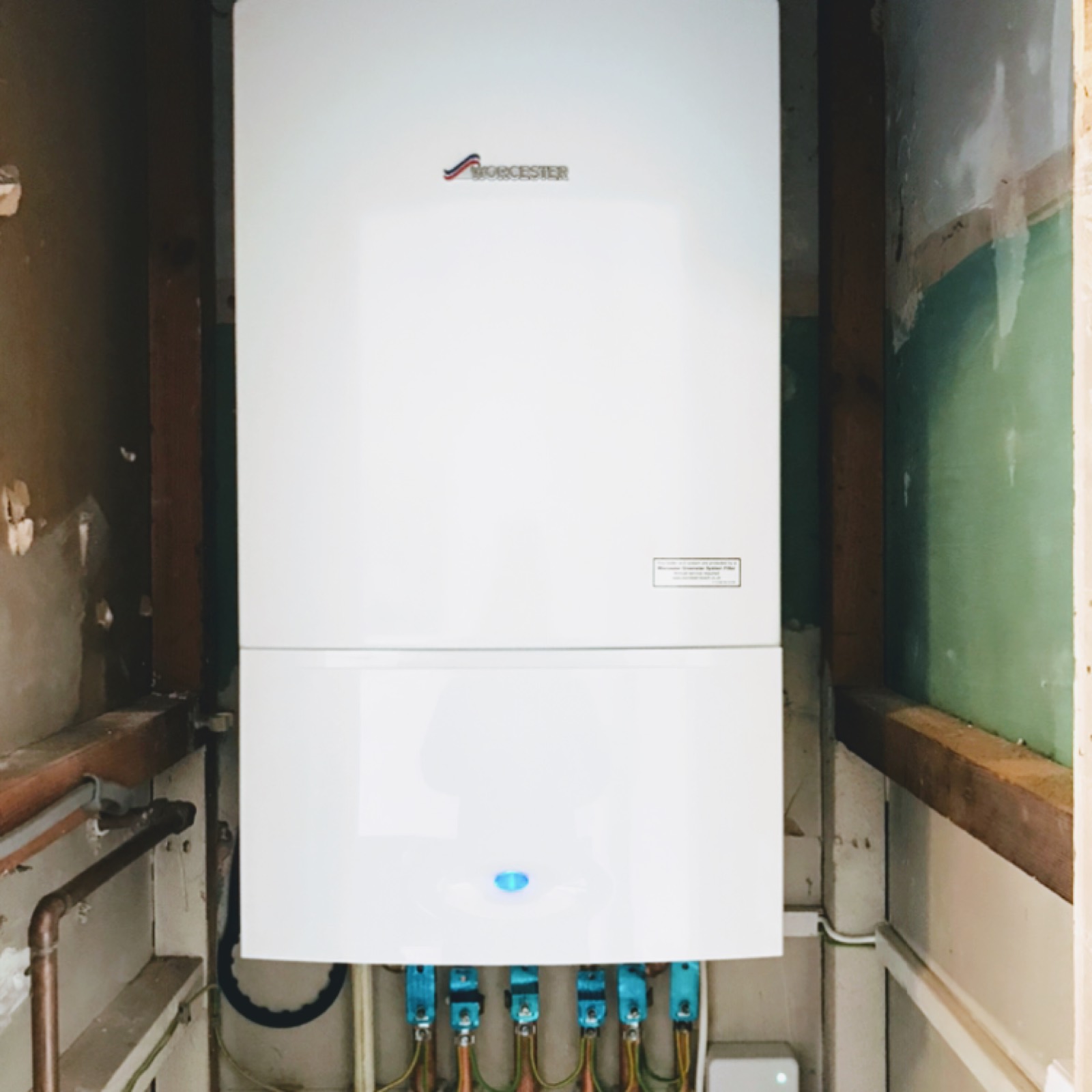A Worcester boiler fitted into a narrow cupboard between studs, with the service valves and pipework colour-tagged underneath so the next engineer knows what is what.