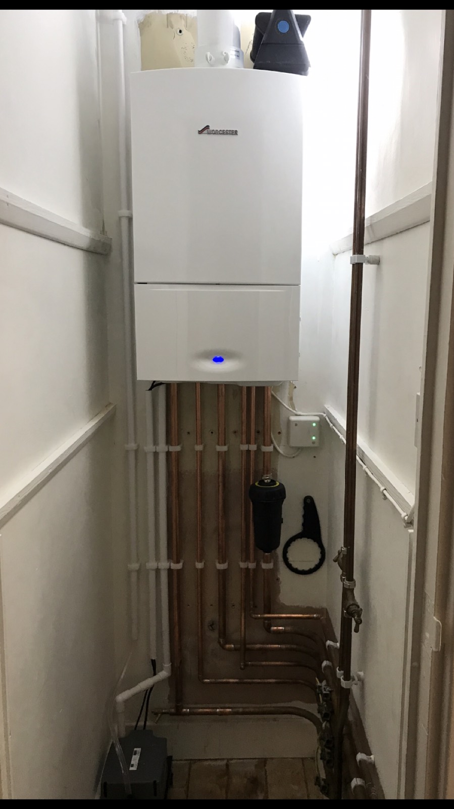A Worcester boiler in an airing cupboard above five parallel copper risers, clipped at even centres with a magnetic filter